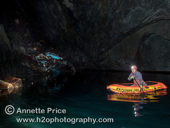 Neil Montgomery paddling a small inflatable boat in Gaewern Slate Mine. North Wales, UK