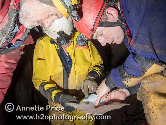Cavers consulting a cave survey map in Slaughter Stream Cave, South Wales, UK