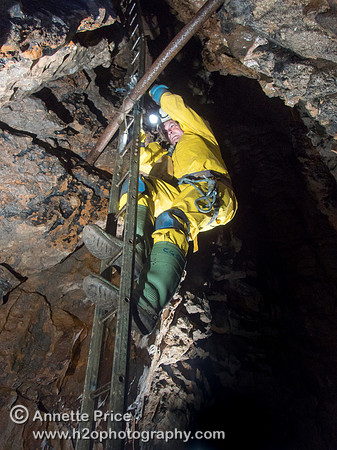 Caver Chris Crowley climbing down a ladder in Slaughter Stream Cave, South Wales, UK