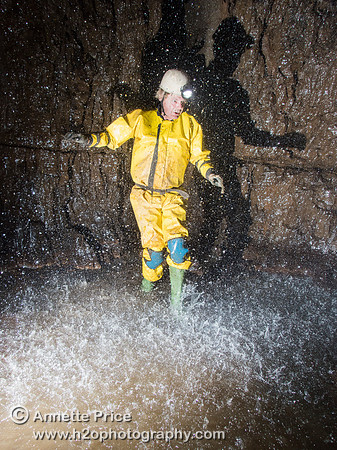Chris Crowley walking under an underground shower.  Slaughter Stream Cave, South Wales, UK