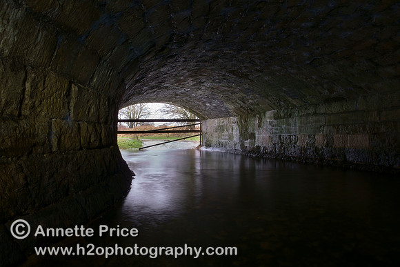 River Thames flowing through one of two tunnels under the A429 Bridge, near Kemble.