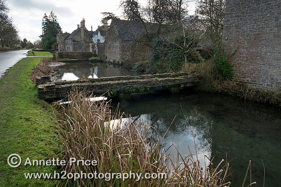 Ashton Keynes.  Most houses on the west side of the High Street have their own bridge over Thames.